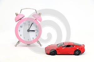 Red car with alarm clock in background.