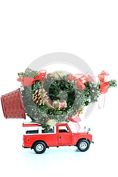 Red car carrying an ornate Christmas pine tree on white background