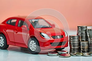 Red car with coins, car tax and financing, car insurance and car loans, concept of saving money on buying a car at a car