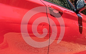 Red car door with dents after crash