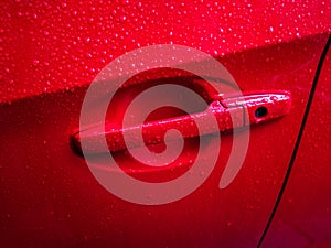 Red car door handle with rain drops