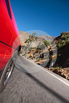 Red car drives through a roadway