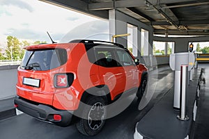 A red car drives into an underground parking lot. Back of red car on parking