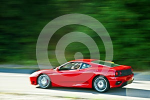 Red car driving fast on country road