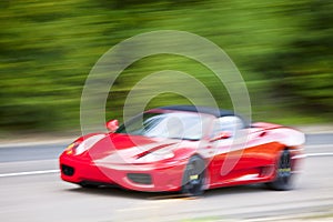 Red car driving fast on country road