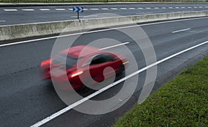 Red car driving fast on the curve of road