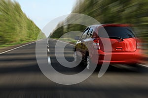 Red car driving at high speed on asphalt road outdoors, motion blur effect