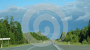 A red car is driving on road. Blue sky, green forest. Journey. Auto travel.