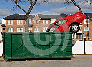 Red car and green dumpster photo