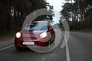 Red car on highway near wood. Road trip