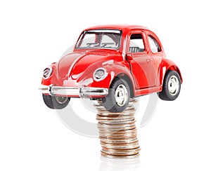 Red car model jacked by a stack of dollar coins on white background