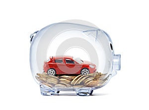 Red car on money inside transparent piggy bank