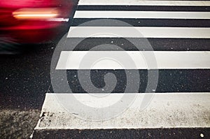 Red car in motion and pedestrian crossing