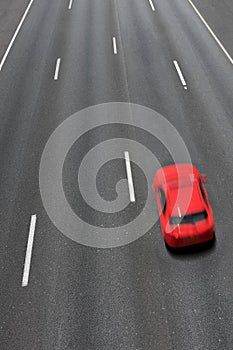 Red car moves fast on highway.