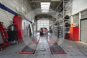 Red car during overhaul in a modern garage with a lift