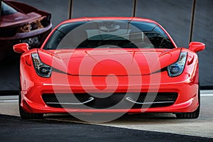 The red car is parked on the asphalt with glass behind it