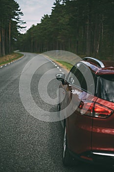 Red car parked on winding road in forest area