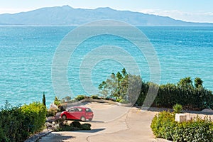 Red car on the road near the ocean on sunny summer day. Red car parked at the beach