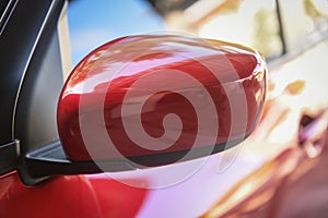 Red car with side rear view mirror on a modern car side mirror front