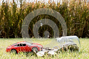 Red car on stack of coin on blurred green natural background. Saving money and investment concept