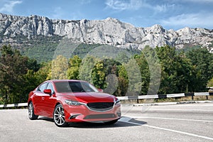 Red car standing on the road near mountains at daytime