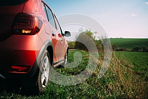 Red car is staying on the grass