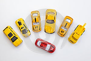 A red car toy surrounded by orange cars