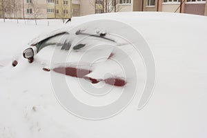 Red car under a large snowdrift, snow storm, winter, blizzard, storm warning, drift