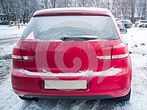 Red car under the snow. Frozen Hatchback standing on snow. winter problems with warm up the car photo