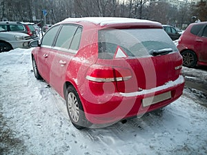 Red car under the snow. Frozen Hatchback standing on snow. winter problems with warm up the car photo