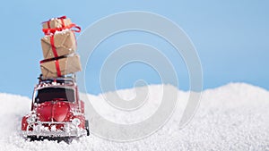 Red car Volkswagen Beetle with present boxes on snow background