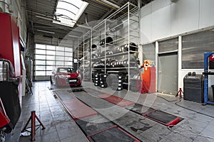 Red car in a workshop with tires. Professional vehicle repair photo