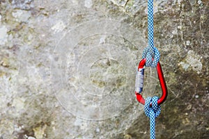 Red carabiner with climbing rope on rocky background photo