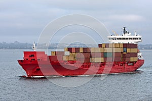 Red cargo container ship at sea.