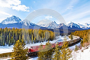 Red cargo train passing through Morant\'s Curve in Banff during Winter