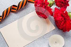 Red carnations and St. George ribbon on a concrete background. Symbol may 9, victory day Copy space