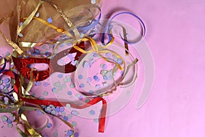Red carnival costume mask on colorful confetti necklace flowers and streamers with space for text photo
