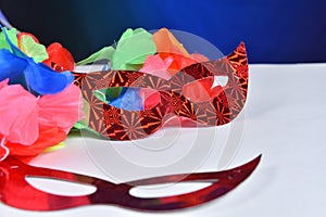 Red carnival costume mask in colorful confetti and streamers on pink background with space for text photo