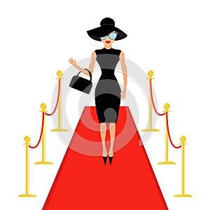 Red carpet and rope barrier golden stanchions turnstile Isolated Woman in black hat, bag, sunglasses waving.