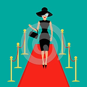 Red carpet and rope barrier golden stanchions turnstile Woman in black hat, bag, sunglasses waving. Rich beautiful celebr