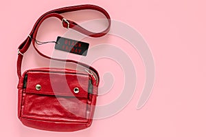 Red carry bag with black price tags on pink background.