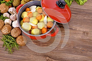 Red casserole dish with winter vegetables and herbs