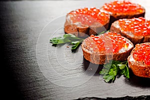 red caviar on black bread with butter. Healthy food. Fish appetizer. dark background