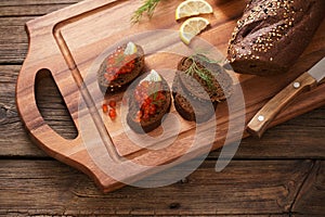 The red caviar with black bread, dill and lemon on  wooden board