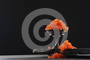 Red caviar in a bowl on a black background. Salmon roe. A delicacy. A delicious dish. The texture of the caviar. Seafood