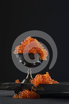 Red caviar in a bowl on a black background. Salmon roe. A delicacy. Delicious food. The texture of the caviar. Seafood