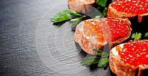 Red caviar on bread on slate background