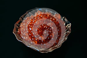 Red caviar in glassware on a black background close up. Gourmet food