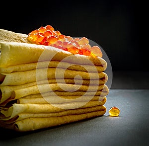 Red caviar on pancakes stack on black