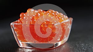 Red caviar rotated over black background. Close-up salmon caviar rotation.